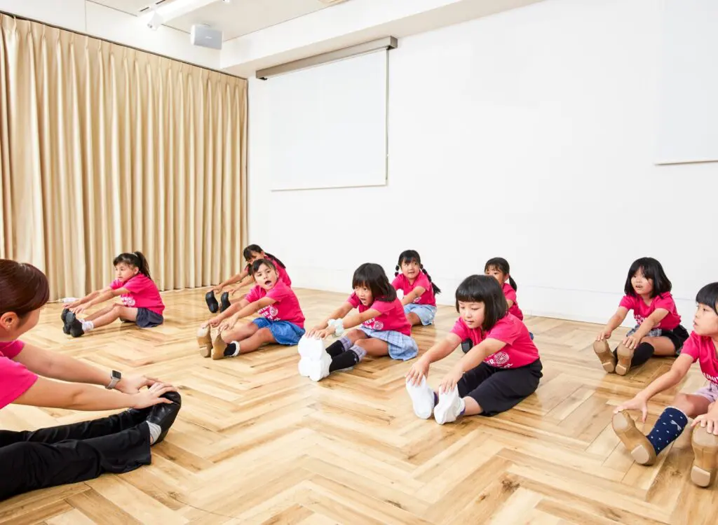 床に座ってストレッチをする子どもたちと講師